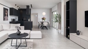 Ein modernes Wohnzimmer mit Sofa, Couchtisch und Essbereich mit Tisch und Stühlen.