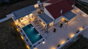 Ein modernes Haus mit Schwimmbad, Sitzgelegenheit im Freien und einem roten Dach.