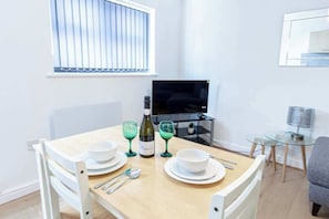 Un coin repas avec une table dressée pour deux personnes, une bouteille de vin et deux verres.