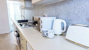 A modern kitchen with a stove, microwave, kettle, and toaster.