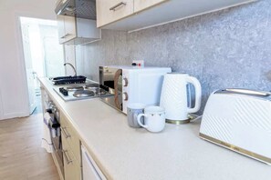 Een moderne keuken met een fornuis, magnetron, waterkoker en broodrooster.