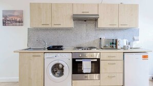 A compact kitchen with a washing machine, oven, and a small refrigerator.