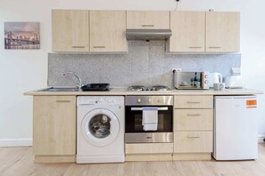 Een praktische keuken met een wasmachine, oven en een kleine koelkast.