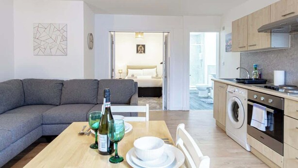 A modern apartment with a living area, kitchenette, and a view of the city.