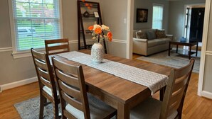 Un coin repas avec une table en bois, des chaises, un vase de fleurs et un lustre.