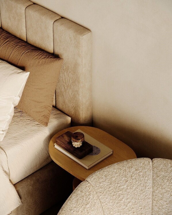 A corner of a room with a beige sofa, a small round table with a book and a decorative item, and a textured ottoman. - Kyoto Suites - Sleep inn Antwerp (Antwerp)