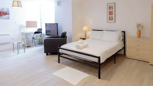 Ein modernes Schlafzimmer mit Bett, Nachttisch, Lampe und Schreibtisch mit Stuhl.