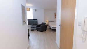 Ein Hotelzimmer mit Fernseher, Sessel, Nachttisch und Bett.