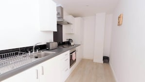 Eine moderne Küche mit weißen Schränken, einer Edelstahlspüle, einem Toaster und einer schwarzen Arbeitsplatte.