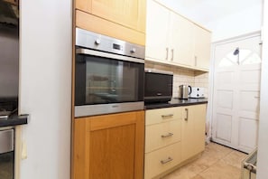 Een keuken met houten kastjes, een magnetron en een oven.