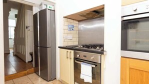 Una cocina con refrigerador, estufa, horno y un cartel que dice 'LIMPIAR DESPUÉS DE USAR'.
