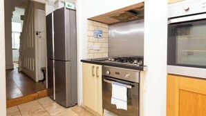 Una cocina con refrigerador, estufa, horno y salpicadero de azulejos.