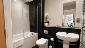 A modern bathroom with a glass-enclosed shower, a white toilet, a sink, and a mirror. - Charming 2BR Flat in Sheffield City Centre (Sheffield)