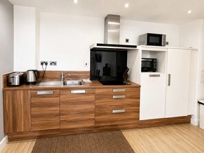 Een moderne keuken met houten kastjes, roestvrijstalen apparatuur en een magnetron op het aanrecht.