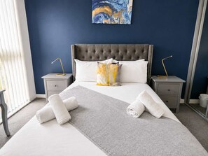 A hotel room with a large bed, two bedside tables, a headboard, and a painting on the wall. - Charming 2BR Flat in Sheffield City Centre (Sheffield)