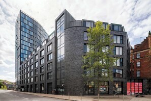 A modern building with a curved facade, large windows, and a tree in front. - Lovely 2BR Apt in Sheffield City Centre (Sheffield)