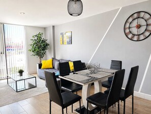 Een moderne eethoek met een tafel met glazen blad, zwarte stoelen en een decoratieve metalen schaal als middelpunt.