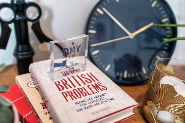 A book titled 'British Problems' on a table with a clock and a decorative glass.