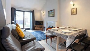 A living room with a sofa, a dining table set for four, a television, and a fireplace. - Spacious House in Sheffield - Great Location! (Sheffield)