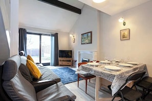 A living room with a sofa, a dining table set for four, a television, and a fireplace. - Spacious House in Sheffield - Great Location! (Sheffield)