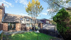A residential backyard with a lawn, a tree, a fence, and a house with a garage. - Spacious House in Sheffield - Great Location! (Sheffield)