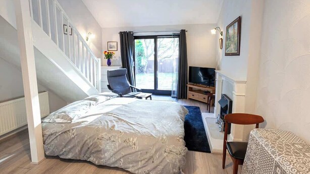 A bedroom with a bed, a chair, a TV, a fireplace, and a staircase. - Spacious House in Sheffield - Great Location! (Sheffield)