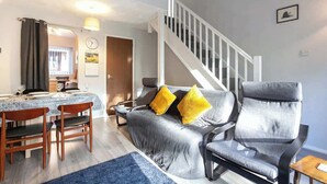 A living room with a sofa, two armchairs, a dining table with chairs, and a staircase. - Spacious House in Sheffield - Great Location! (Sheffield)