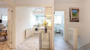 Una cocina moderna con lavadora, una mesa de vidrio y un jarrón, y vistas al exterior.