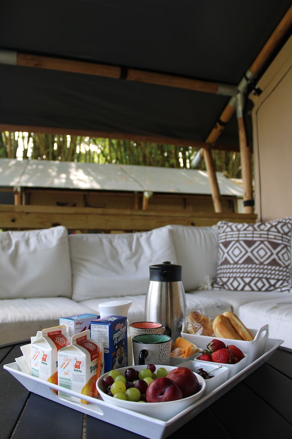 A breakfast tray with milk cartons, juice, fruits, and bread on a table in a room with a sofa and patterned cushions. - Jardin al Bosque (San Juan)