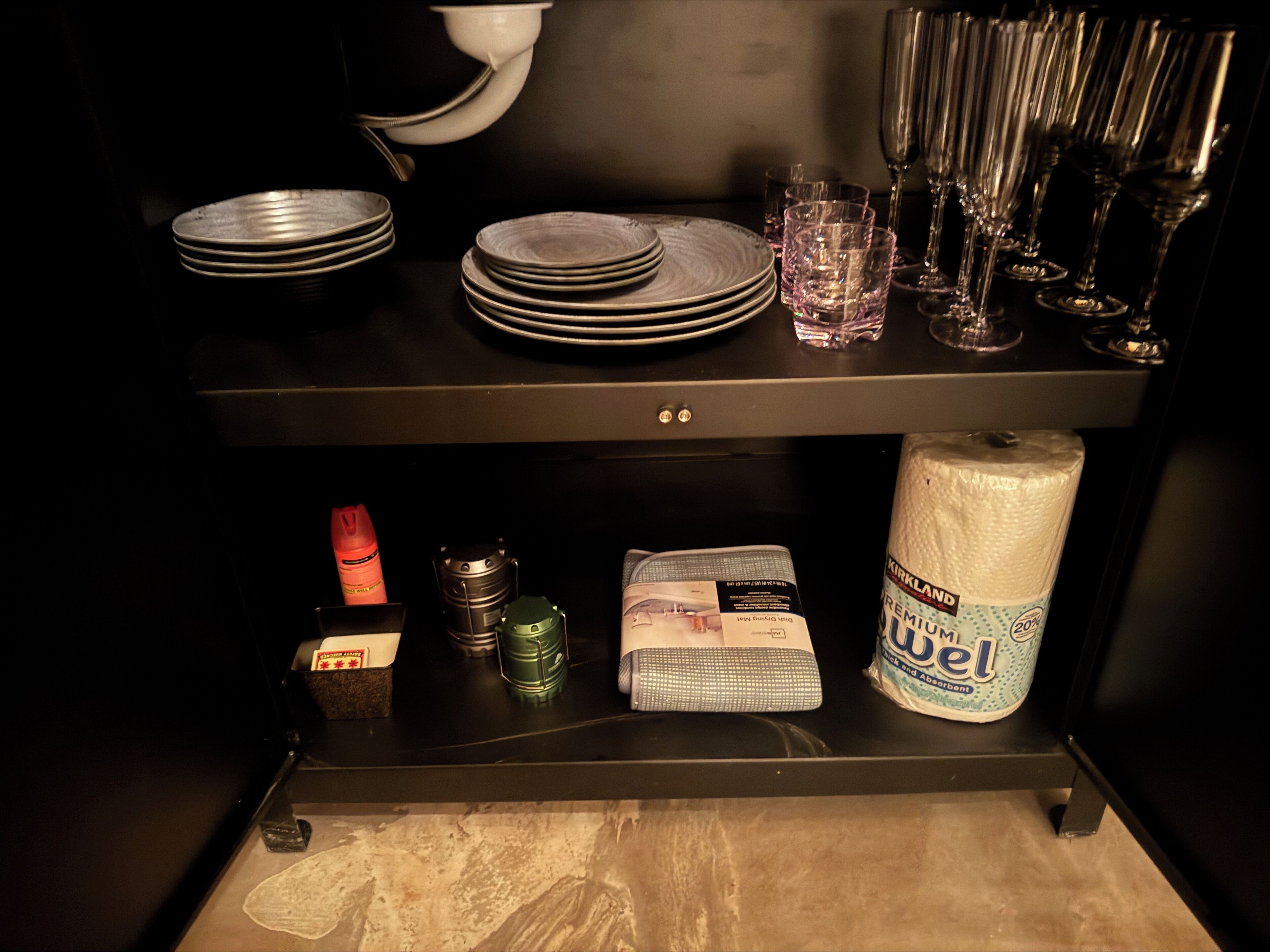 Una encimera de cocina con platos apilados, vasos y un rollo de servilletas de papel.