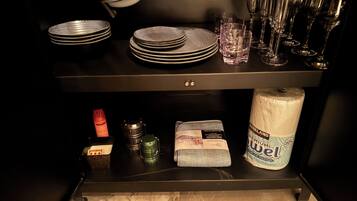 Een keukentafel met een stapel borden, glazen en een rol keukenpapier.