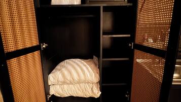 A compact, open wardrobe with a bed inside, featuring a control panel and a white pillow.