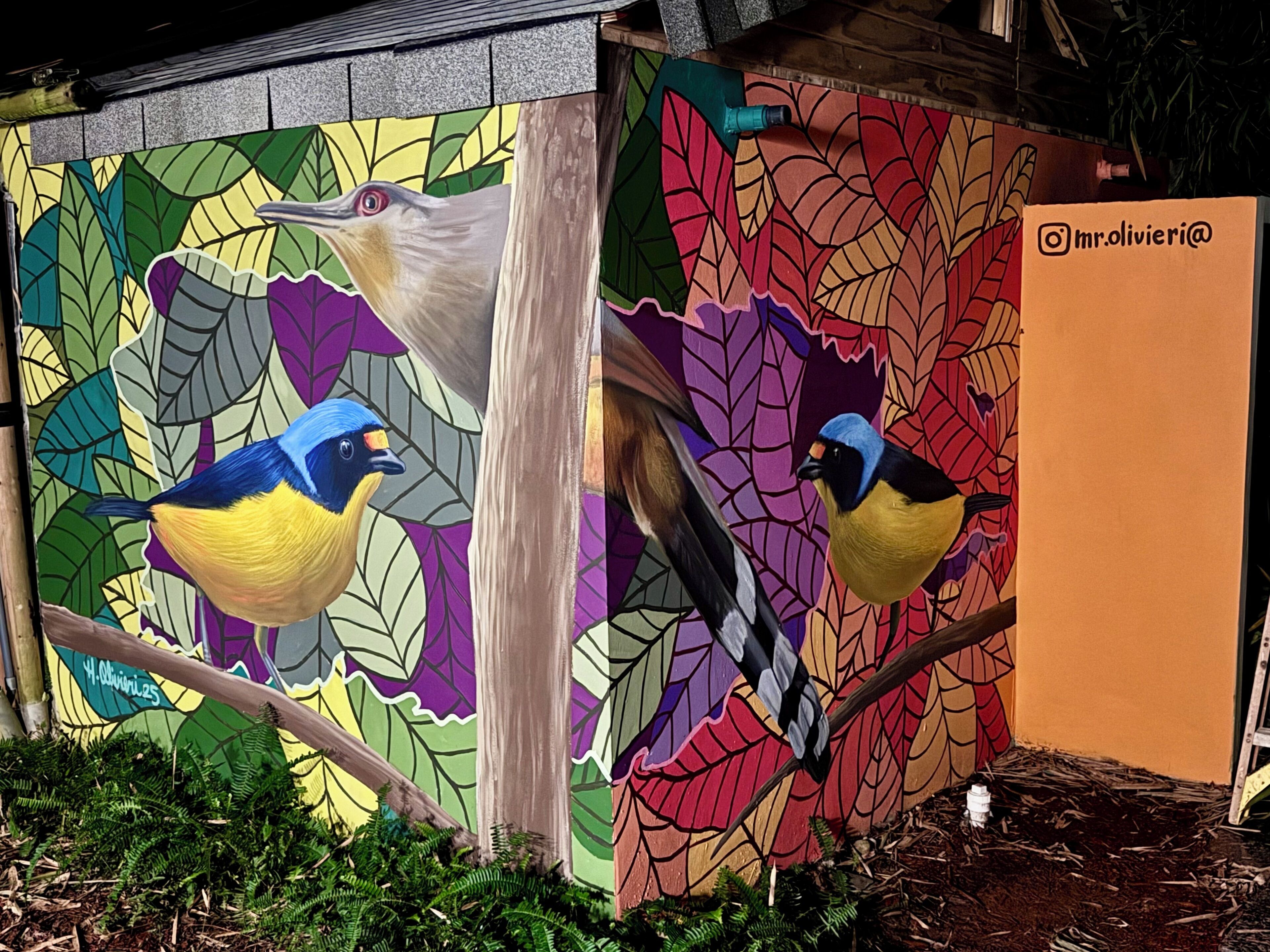 Une fresque représentant des oiseaux sur un mur, avec une structure en bois au premier plan.