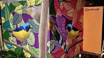 Une fresque représentant des oiseaux sur un mur, avec une structure en bois au premier plan.