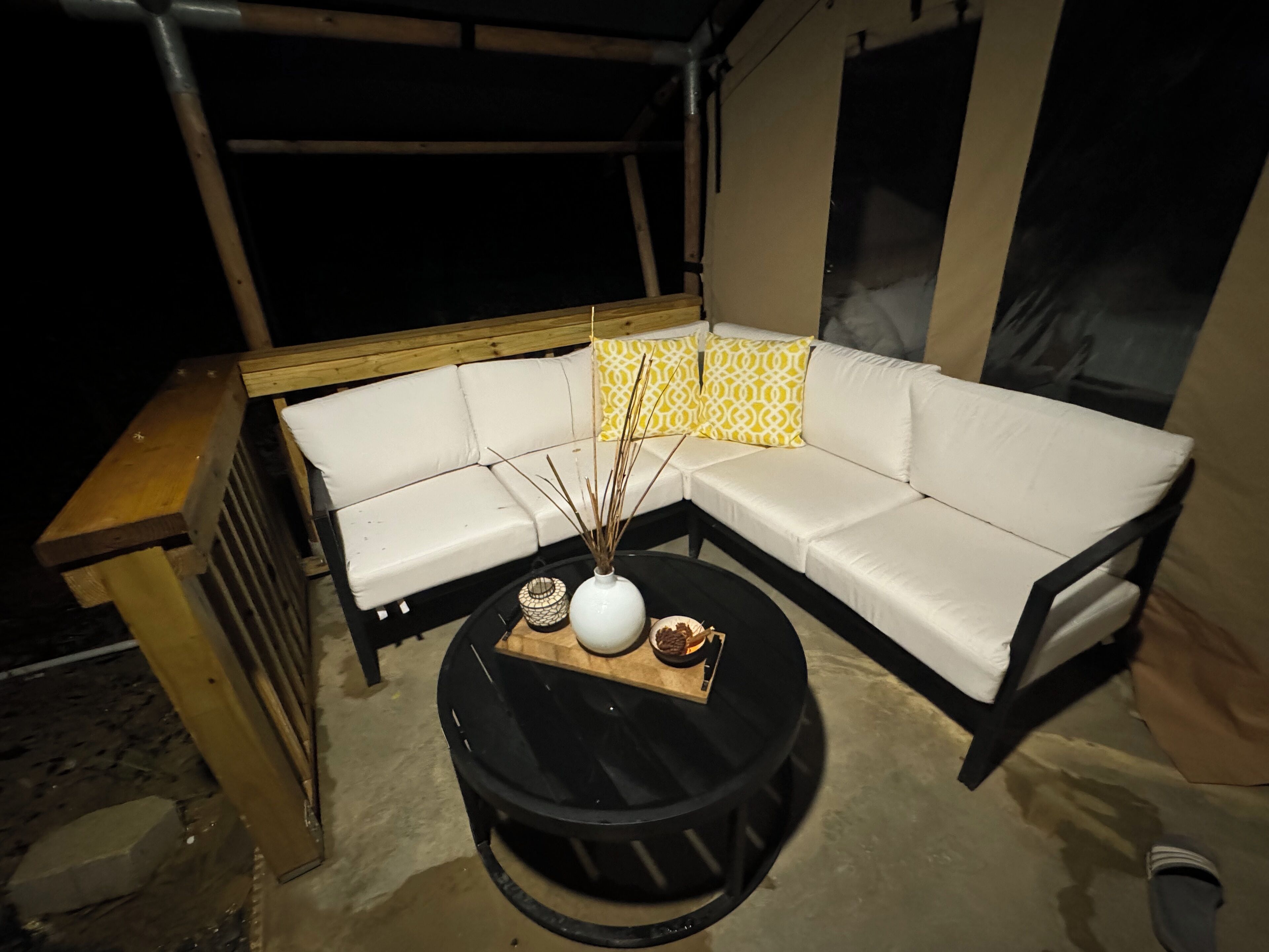 Un canapé modulable, accompagné d’une table d’appoint en bois et d’une table ronde noire agrémentée d’objets décoratifs.