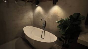 Ein modernes Badezimmer mit einer freistehenden Badewanne, einem Wandarmaturen und einem Blumentopf.