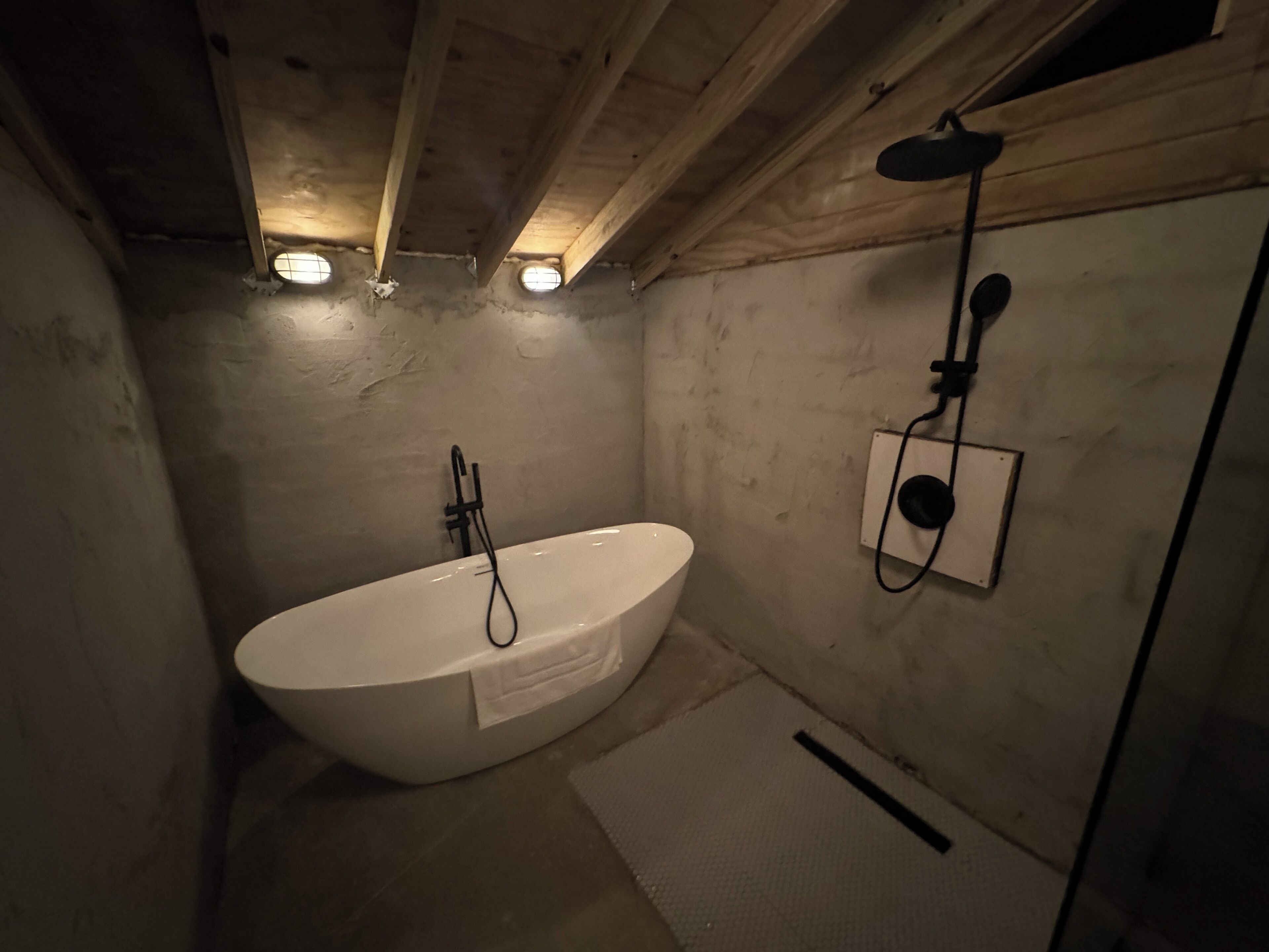 A small, dimly lit bathroom with a white bathtub, a shower, and a single light fixture on the ceiling.