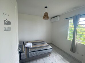 Cozy retreat with a single bed, featuring a striped bedding pattern, and a window with a curtain.