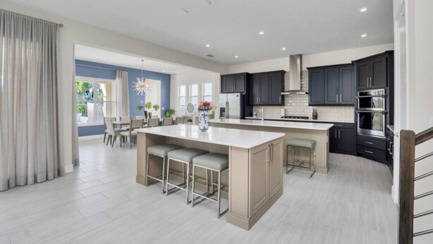 A modern kitchen with dark cabinets, a large island, and stainless steel appliances. - Stunning and luxe Bears Den Luxury Villa w/ Outdoor Kitchen near Disney (Kissimmee)