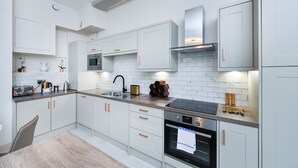 Une cuisine moderne avec des meubles blancs, un four à micro-ondes, une cuisinière et un évier.