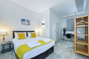 A modern hotel room with a large bed, bedside lamps, a desk, and a wardrobe. - Byard Lane (Nottingham)