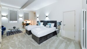 Une chambre d’hôtel moderne équipée de deux lits, d’un bureau, d’une chaise et d’une petite table.