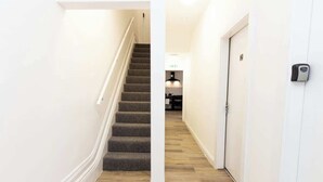 A hallway with a carpeted staircase, a door with a lock, and a light fixture. - Cosy Large Ensuite Room in the Heart of Oldham (Oldham)