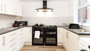 A kitchen with white cabinets, a double oven, a microwave, and a window. - Cosy Large Ensuite Room in the Heart of Oldham (Oldham)