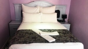 Una cama bien hecha con una colcha de estampado floral y una toalla doblada encima.