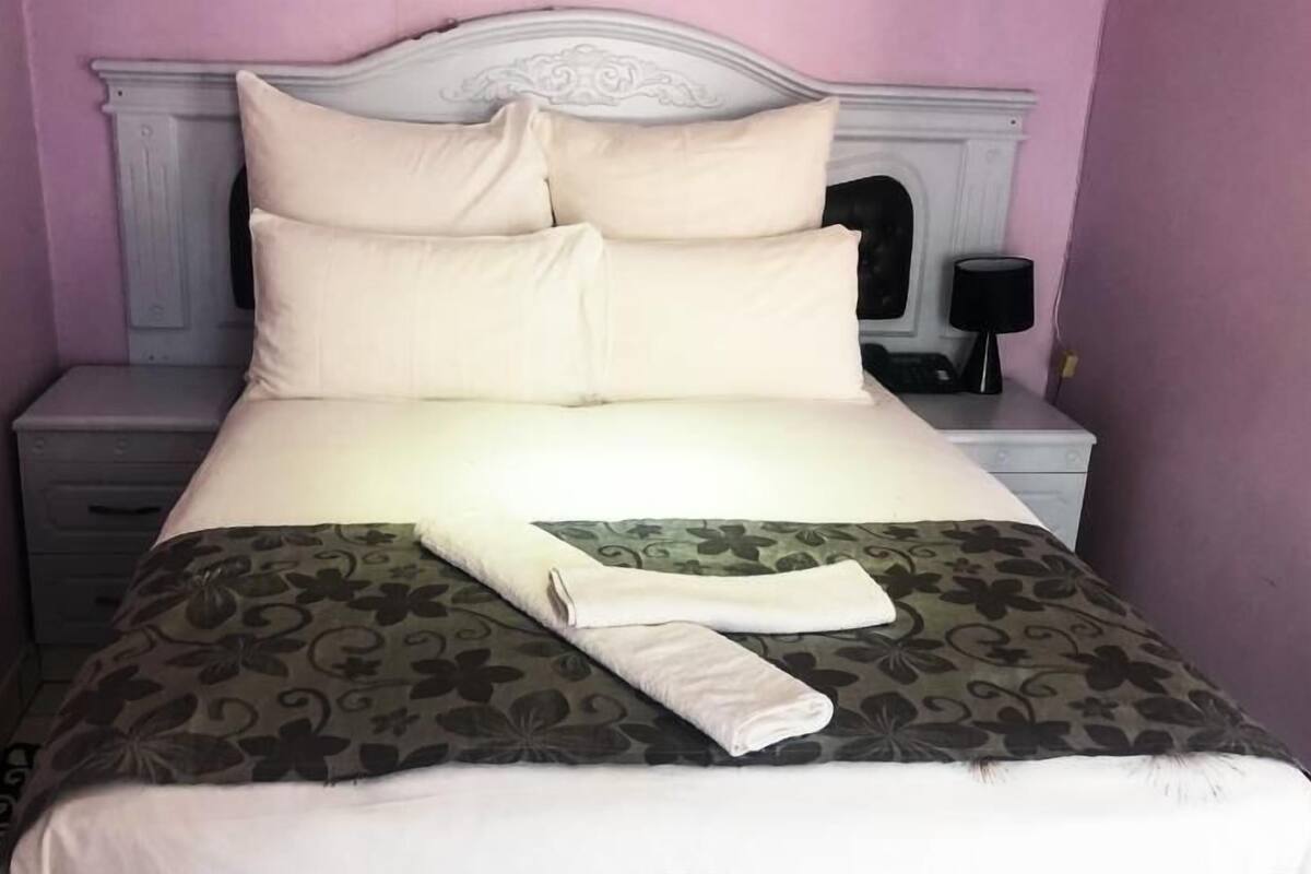 A neatly made bed with a floral-patterned bedspread and a folded towel on top.