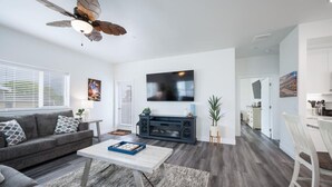 Un salon moderne avec un canapé gris, une table basse et un téléviseur fixé au mur.