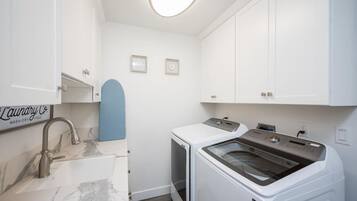 A laundry room with a sink, two washing machines, and a dryer.