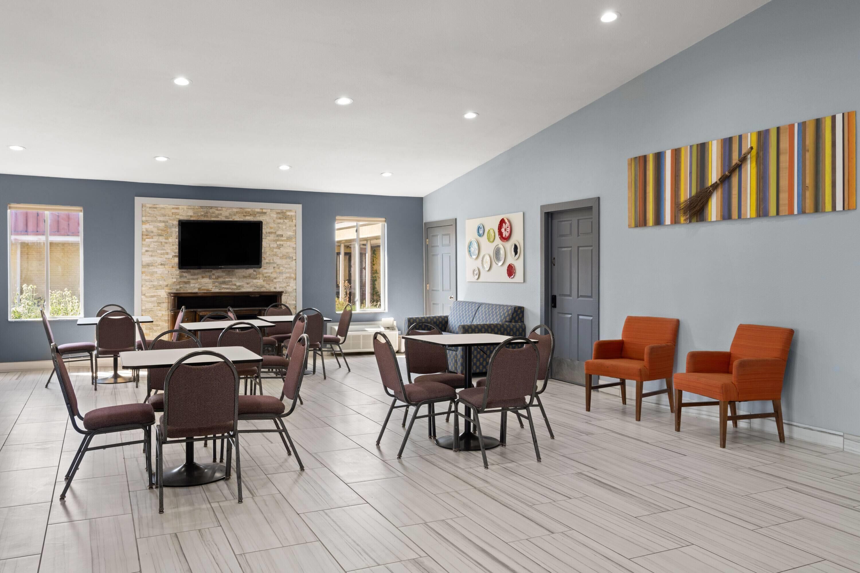 Un comedor con mesas y sillas, chimenea, televisor de pantalla plana y obras de arte en las paredes.