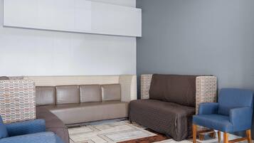 A living room with a sofa, armchairs, patterned cushions, and a patterned rug.